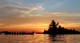 People in a canoe on the lake during sunset