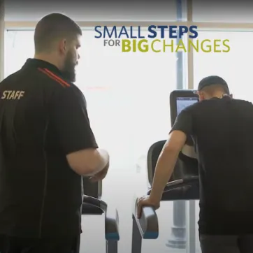 Two people are standing on treadmills with one person directing the other one. The Small Steps for Big Changes logo is above the second person.