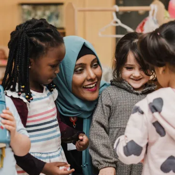 An early childhood educator is smiling with 3 children